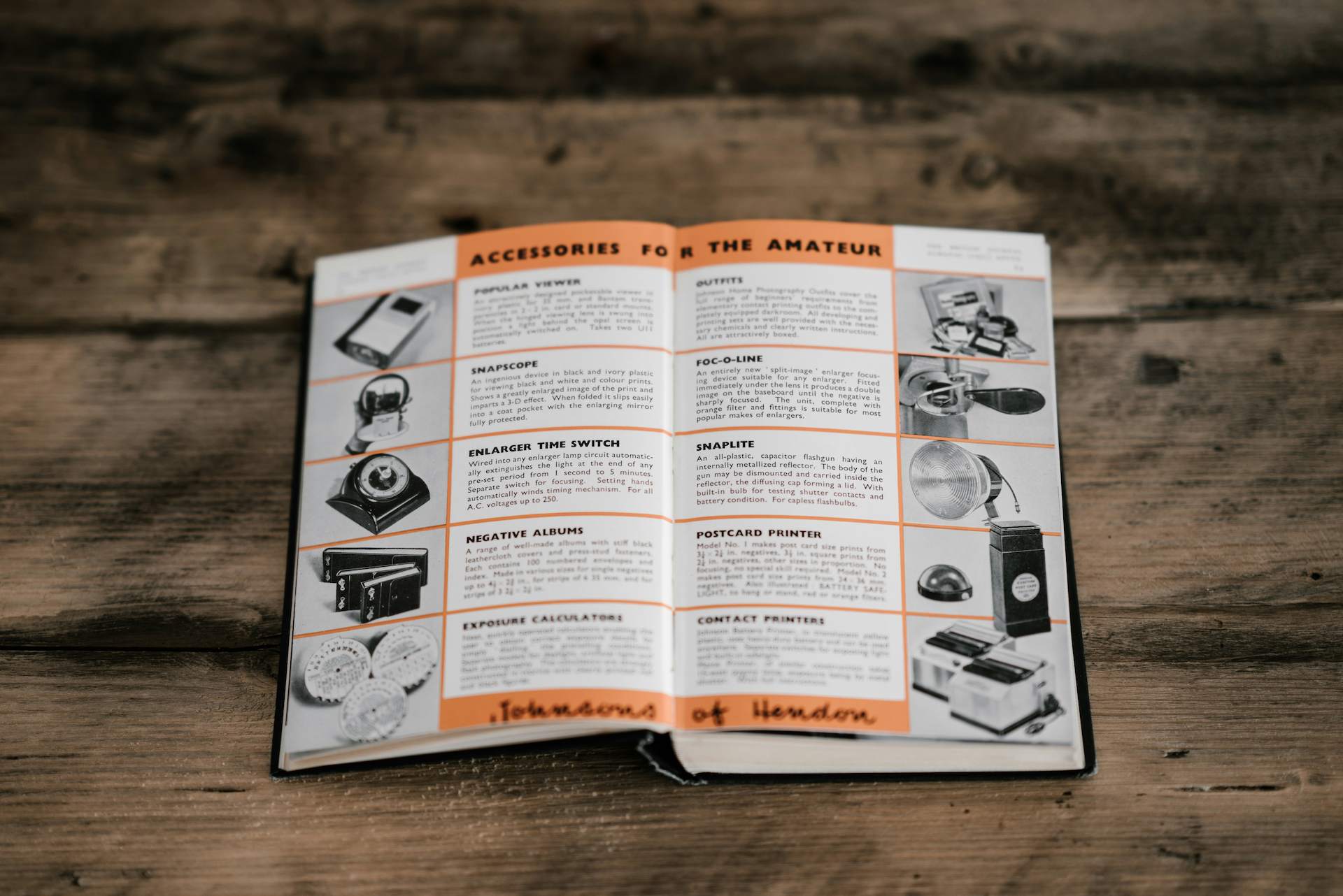 Open technical manual or product guide showing equipment accessories and descriptions on a wooden table