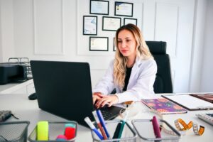 Healthcare professional reviewing documentation on a laptop in a medical office, illustrating healthcare technical writing, compliance, and documentation management.