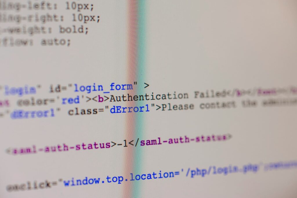 Close-up photograph of computer code on a screen showing an authentication failure message, with HTML tags and a SAML authentication status error visible in the source code. The image has a shallow depth of field, with only parts of the code in sharp focus.