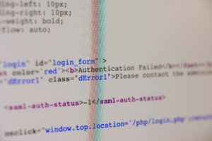 Close-up photograph of computer code on a screen showing an authentication failure message, with HTML tags and a SAML authentication status error visible in the source code. The image has a shallow depth of field, with only parts of the code in sharp focus.