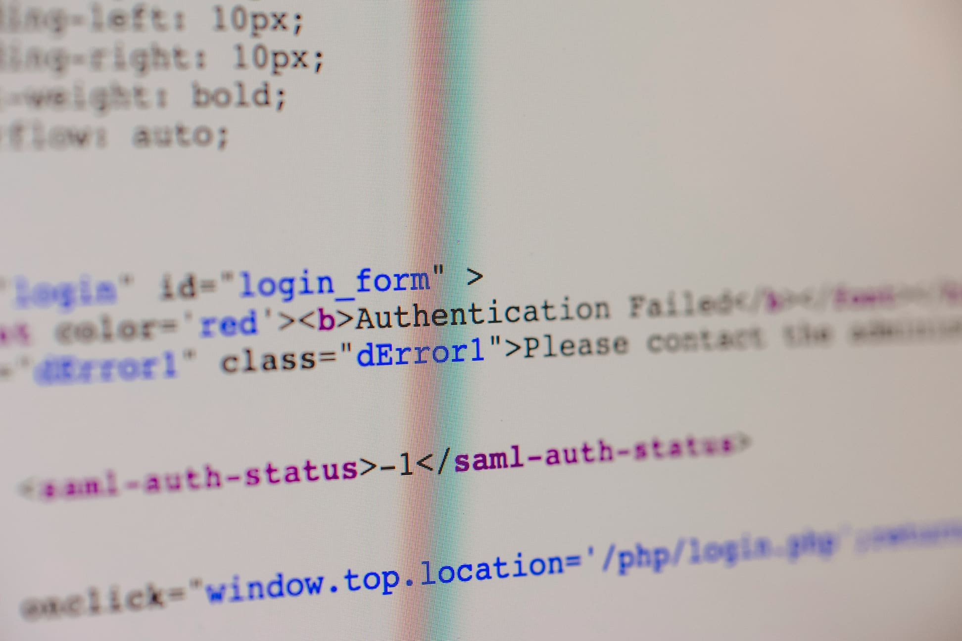 Close-up photograph of computer code on a screen showing an authentication failure message, with HTML tags and a SAML authentication status error visible in the source code. The image has a shallow depth of field, with only parts of the code in sharp focus.