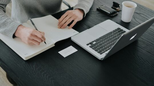 Technical documentation writer creating process documentation and business procedures on a laptop.