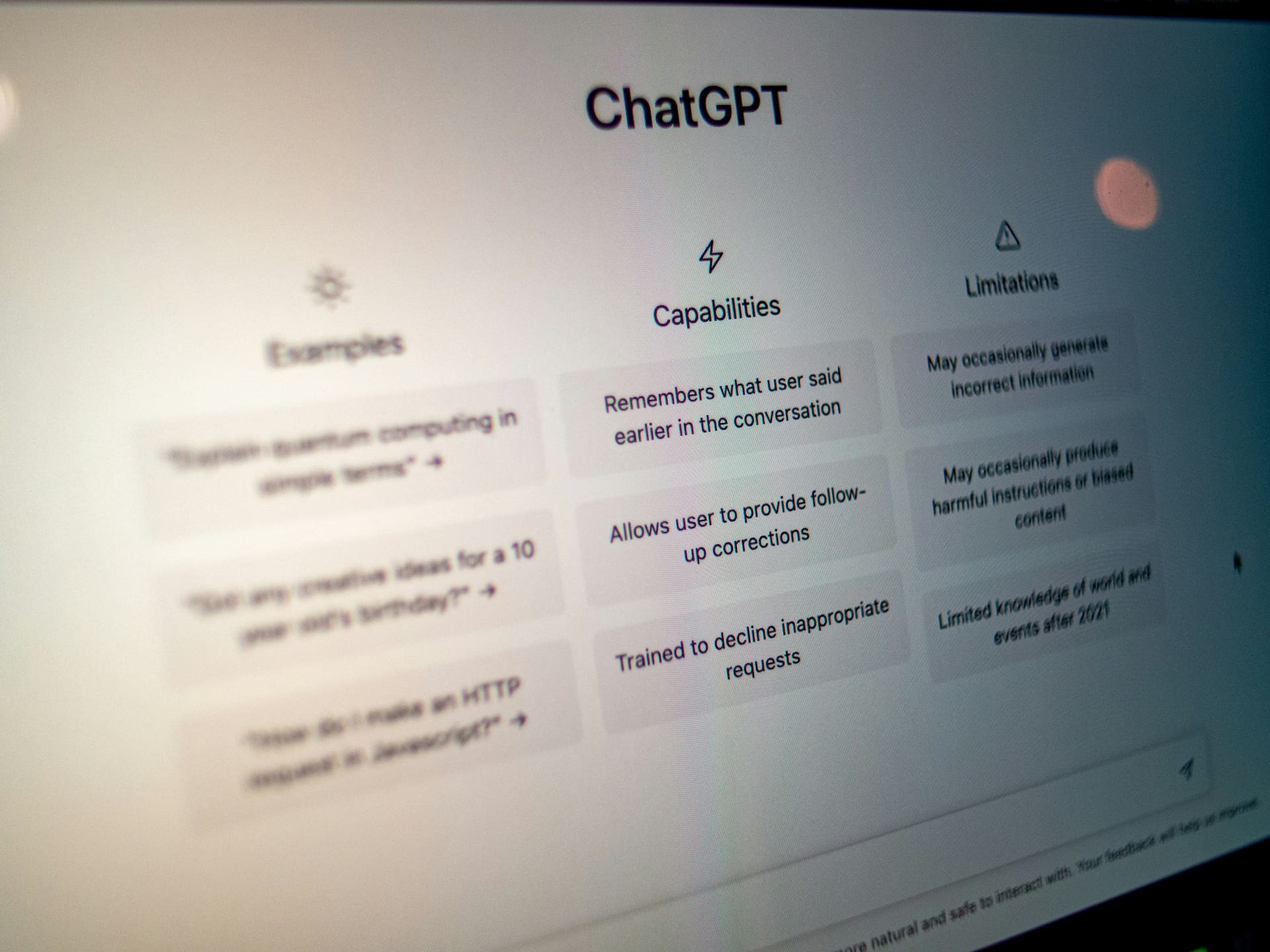 Close-up of the ChatGPT home screen displaying example prompts, capabilities, and limitations on a computer monitor.