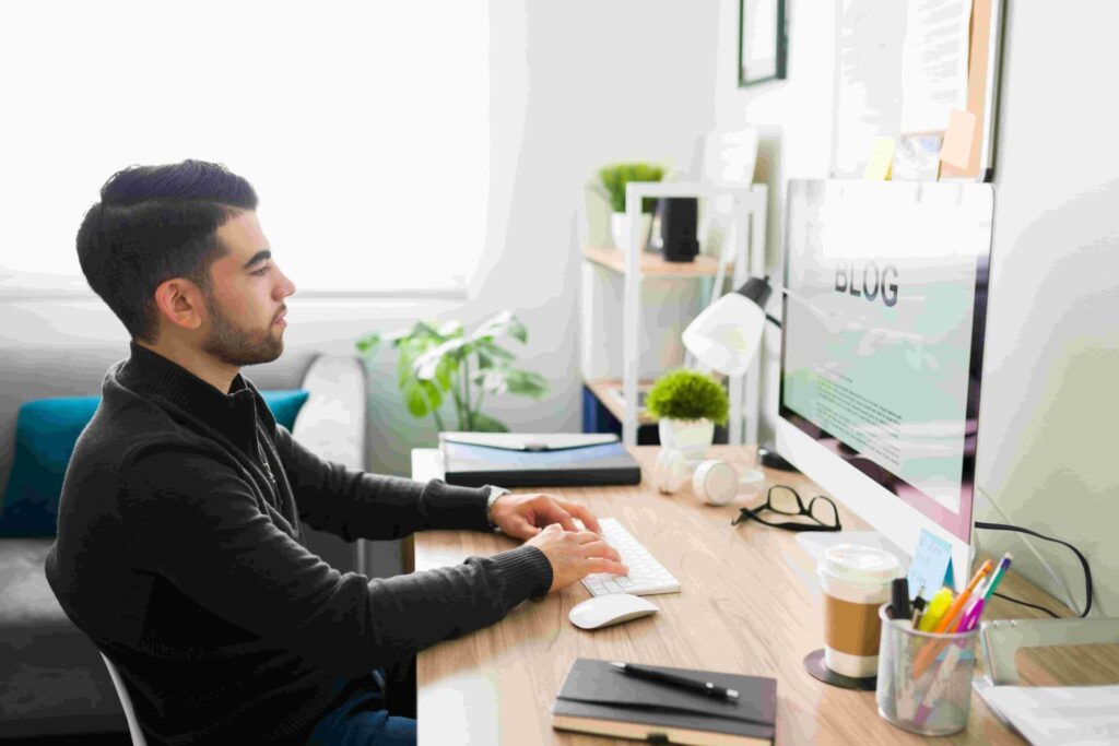 Marketing technical writer creating a blog post on a desktop computer in a modern office workspace with a notebook, coffee, and office supplies.