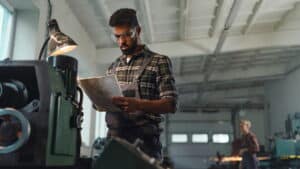 Manufacturing employee reviewing an SOP document beside industrial equipment