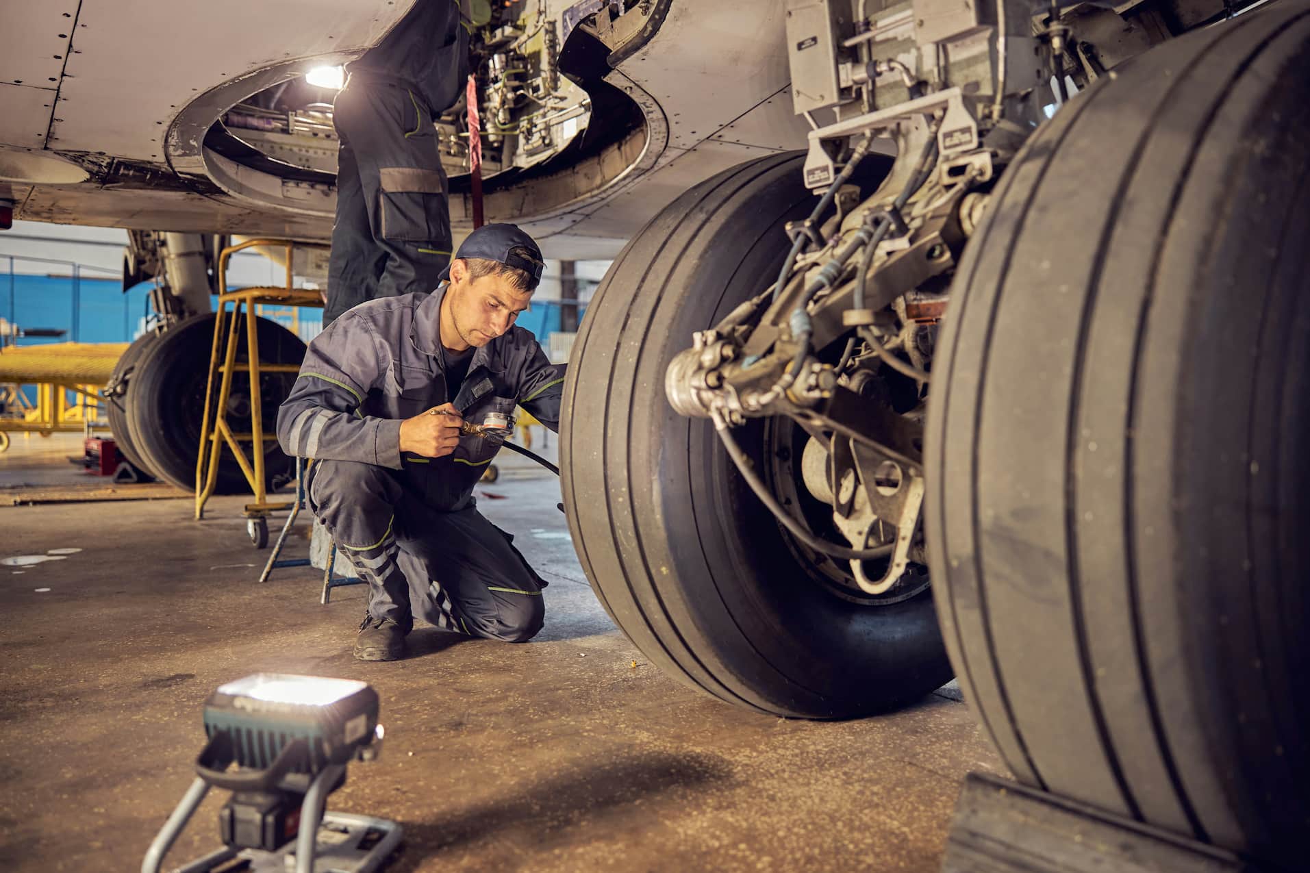 Aviation maintenance technician inspecting an aircraft landing gear during routine maintenance.