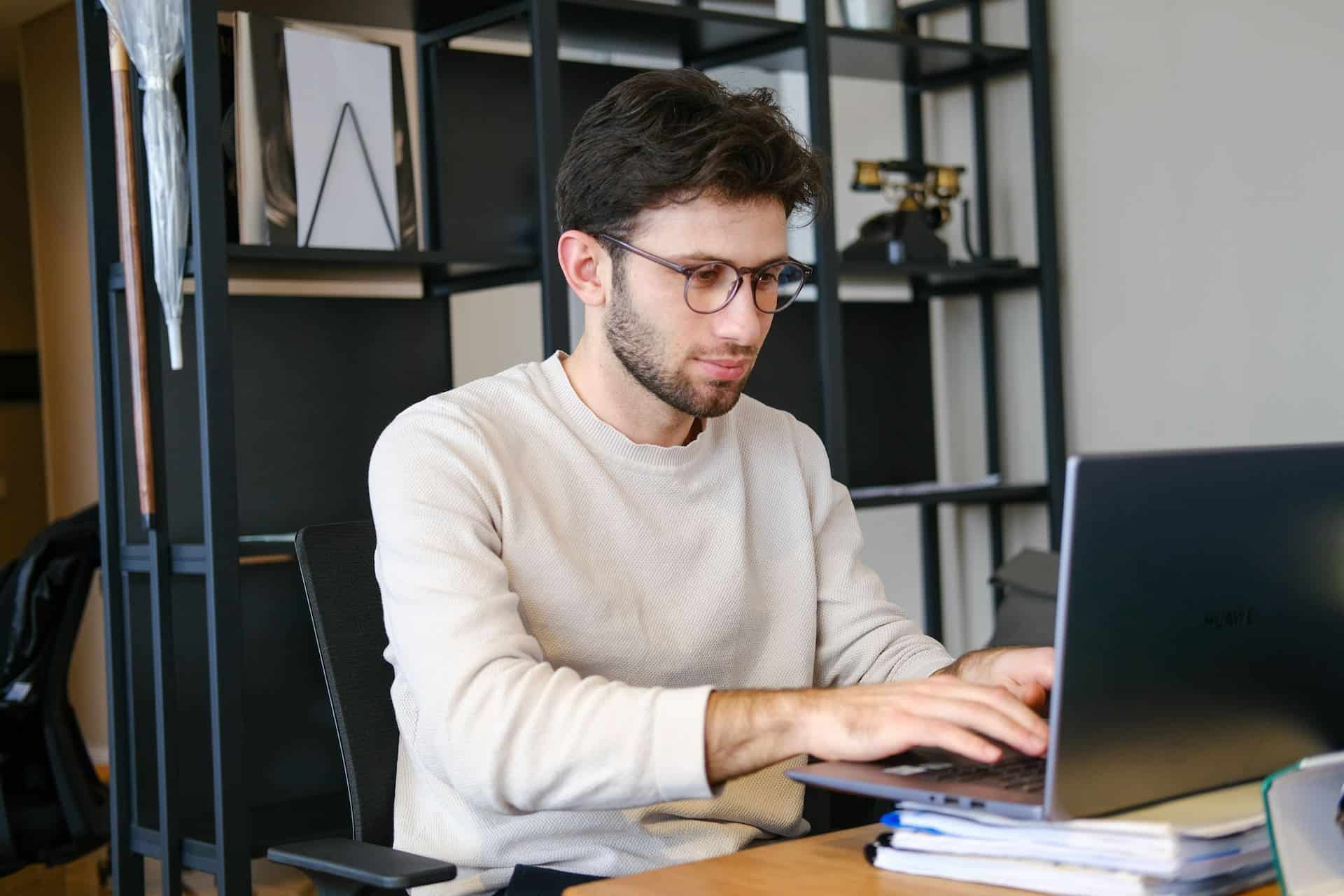 Technical writer working on a laptop in a modern office, creating documentation and technical content.