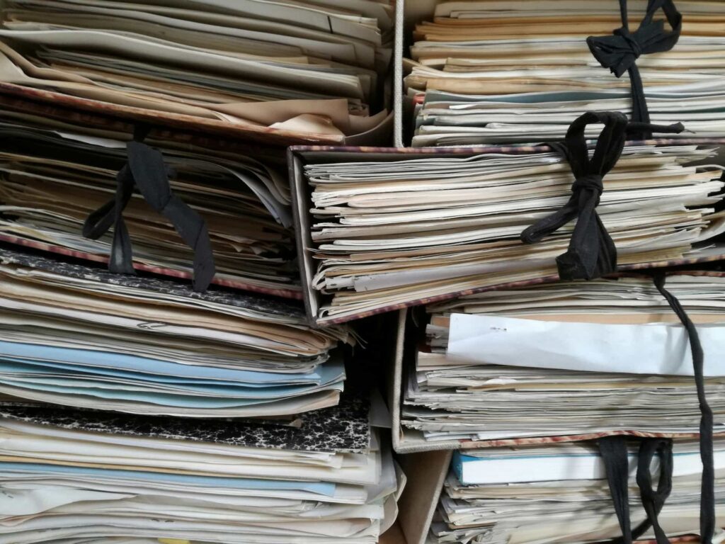 Stacks of paper documents and folders illustrating disorganized technical documentation and record management.