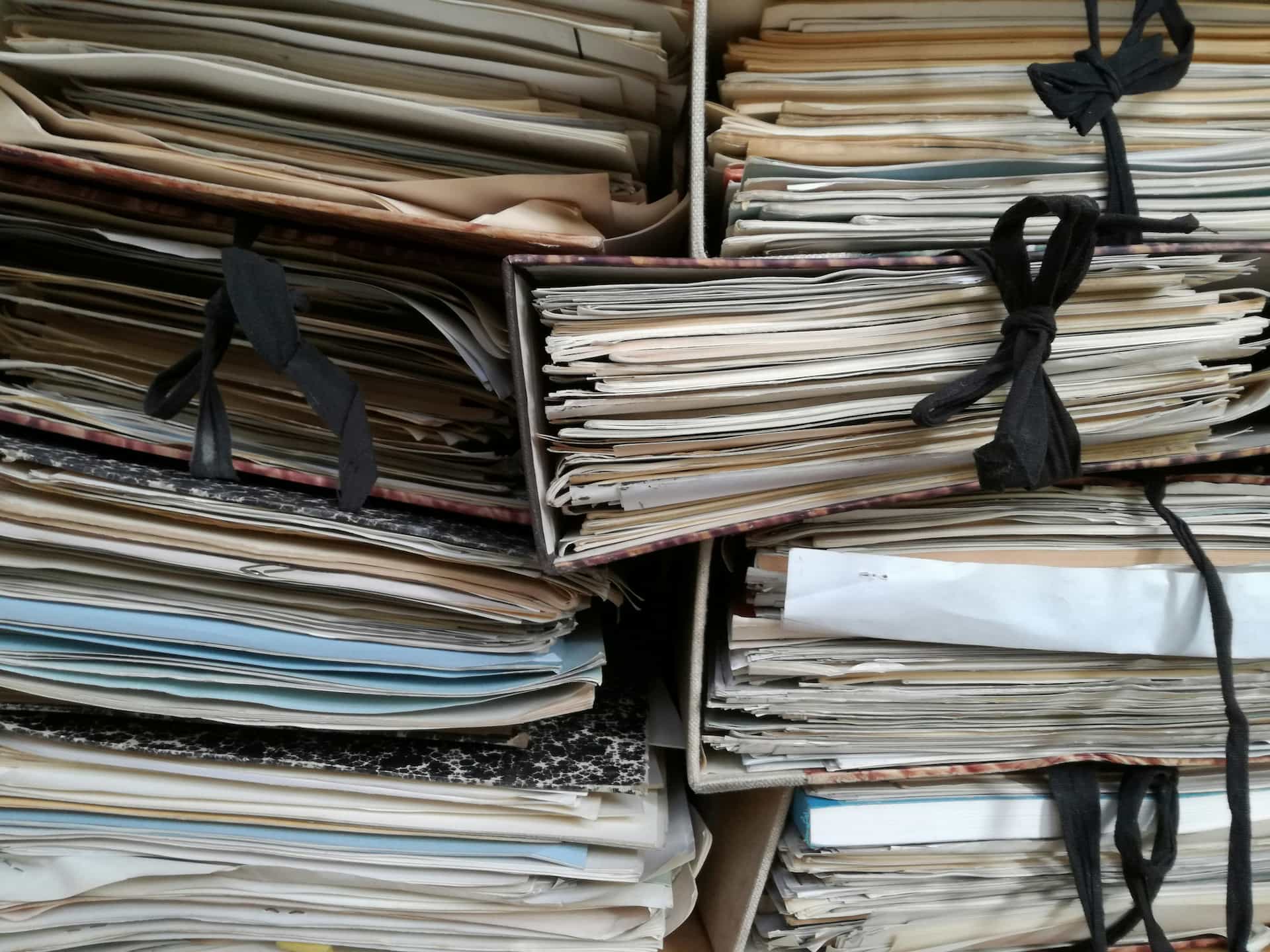 Stacks of paper documents and folders illustrating disorganized technical documentation and record management.
