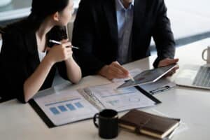 Business professionals reviewing resource planning data and performance charts on a tablet during a meeting.